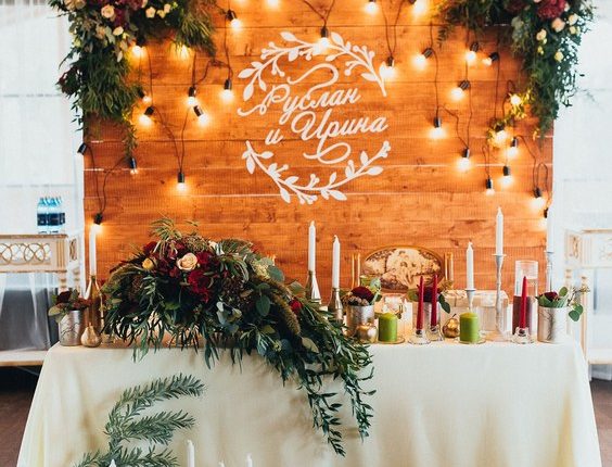 rustic wood backdrop and greenery sweetheart table for indoor wedding reception