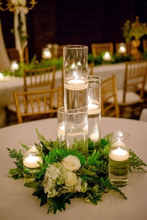 clear glass vases with floating candles displayed with ivory flowers + greenery