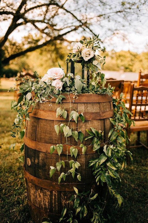 Old barrels with pink flowers, draping greenery and candles