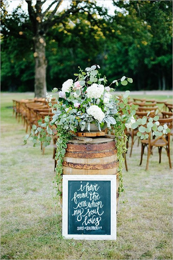 rustic wine barrel wedding decor with greenery arrangements