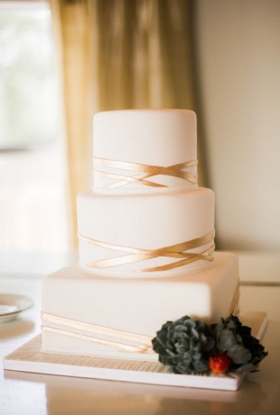 A three-tiered, square and round wedding cake with geometric gold stripes, from Cakes by Gina