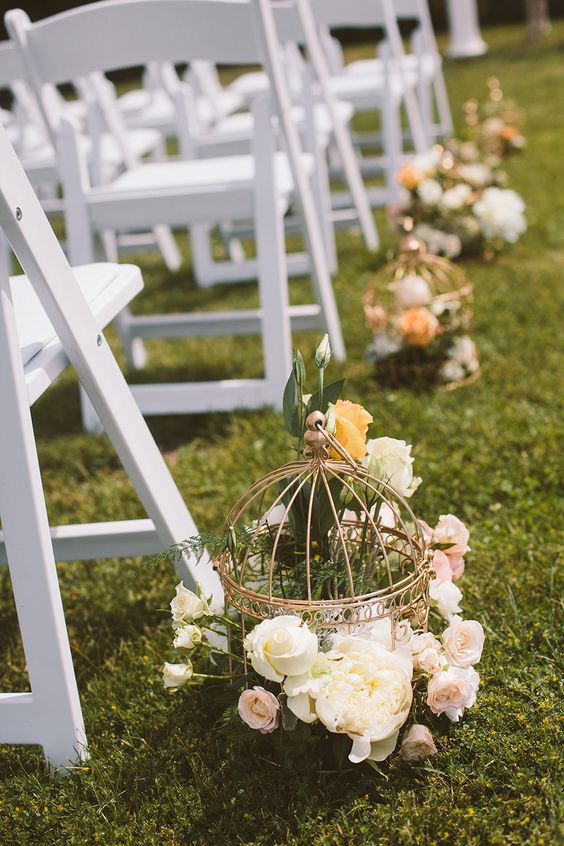 Vintage birdcages lined the aisle and were filled with flowers for a romantic look