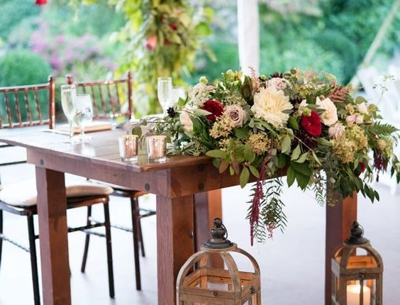Wedding reception sweetheart table with wooden farm table, lanterns, candles