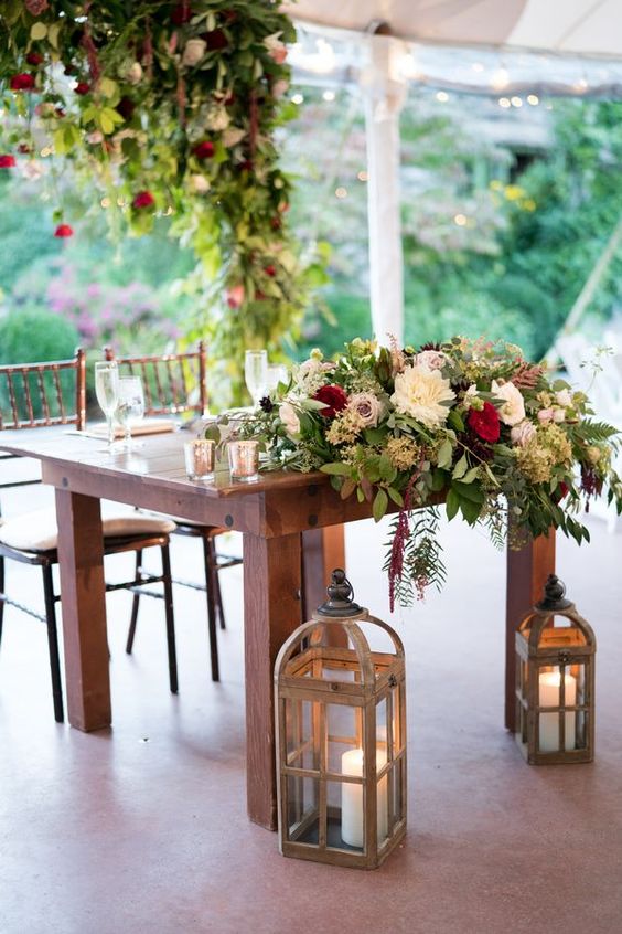 Wedding reception sweetheart table with wooden farm table, lanterns, candles
