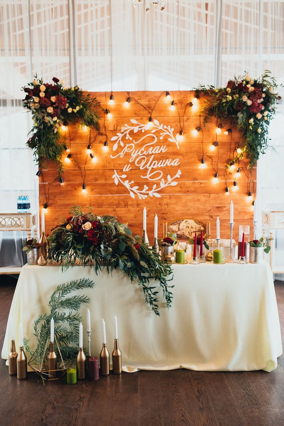 rustic wood backdrop and greenery sweetheart table for indoor wedding reception