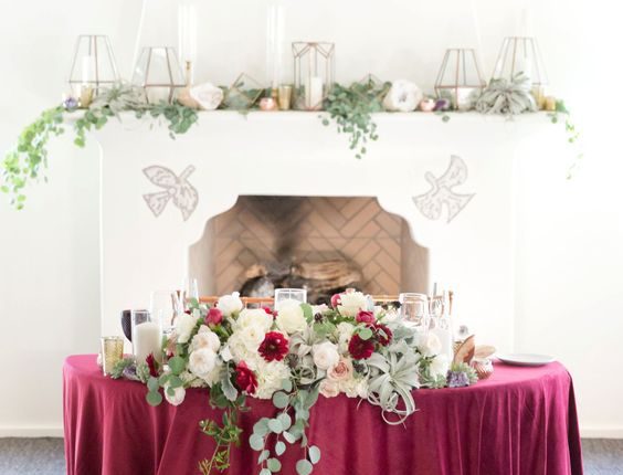 wedding head table with rich burgundy color tones and floral greenery
