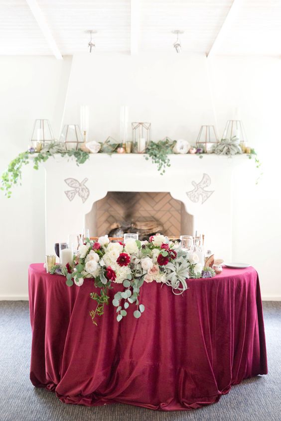 wedding head table with rich burgundy color tones and floral greenery