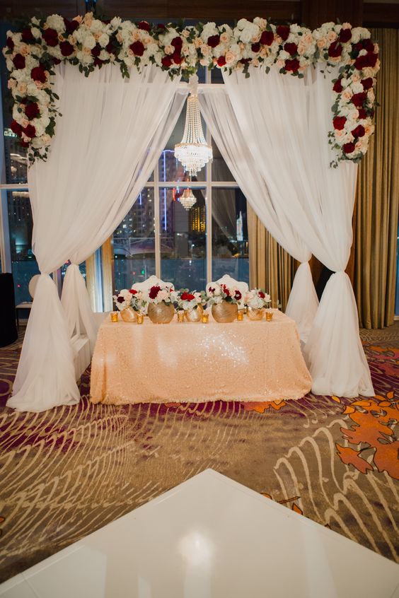 Sweetheart table under beautiful arch with lush floral garland