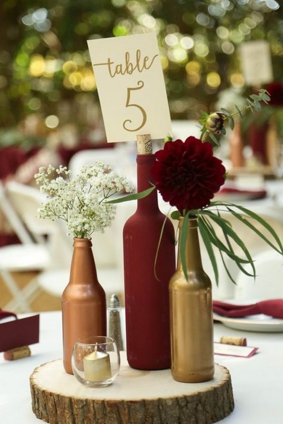 Gold and burgundy wine bottle centerpiece on wood round