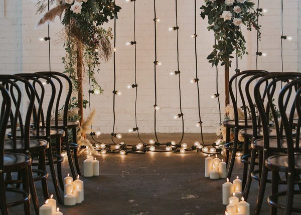 indoor floral wedding arch with pampas plumes and festoon lights