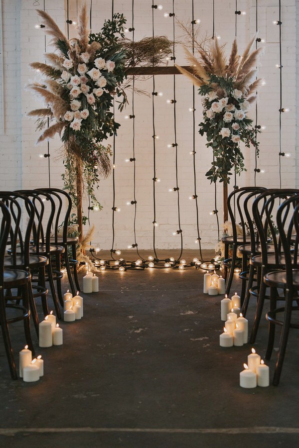 indoor floral wedding arch with pampas plumes and festoon lights