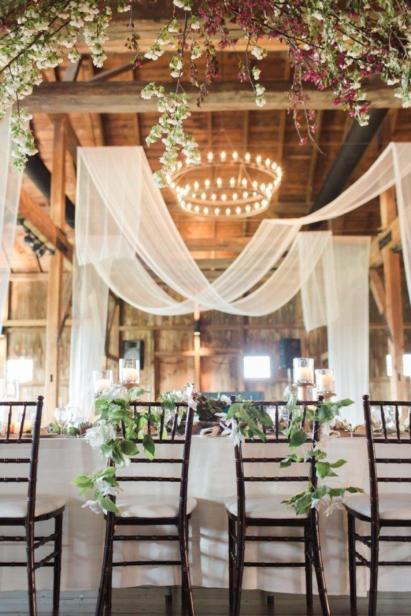 Rustic barn wedding reception space with draped fabric decor