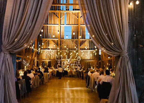 barn wedding decro with curtains, strung lights, candles, burlap