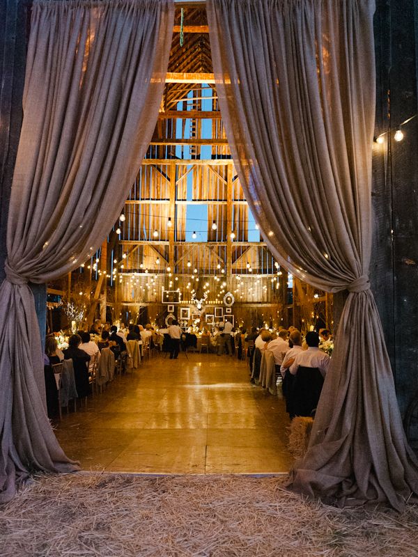 barn wedding decro with curtains, strung lights, candles, burlap