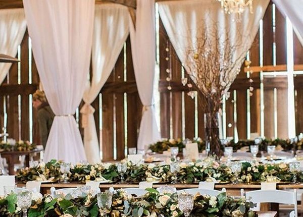 rustic barn wedding reception with greenery on wooden table
