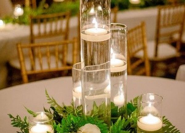 clear glass vases with floating candles displayed with ivory flowers + greenery