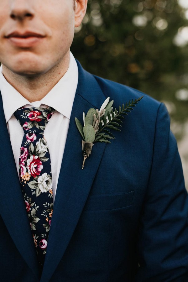 navy blue groom attire with floral tie and boutonniere