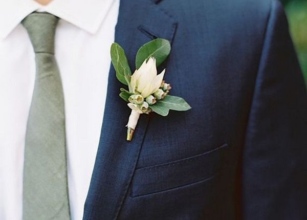 navy blue groom attire with green tie and boutonniere