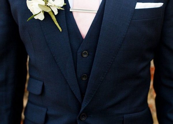 navy blue groom attire with pink tie and greenery boutonniere