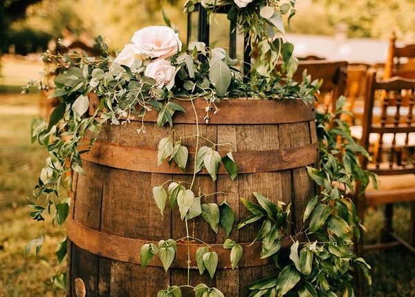 Old barrels with pink flowers, draping greenery and candles