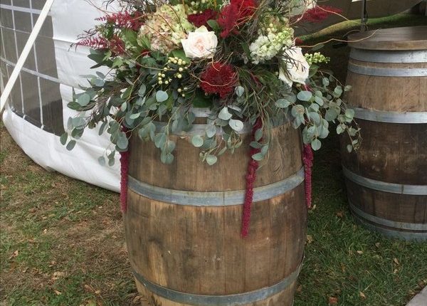 Vineyard themed wedding with rustic arrangements on oversized wine barrels