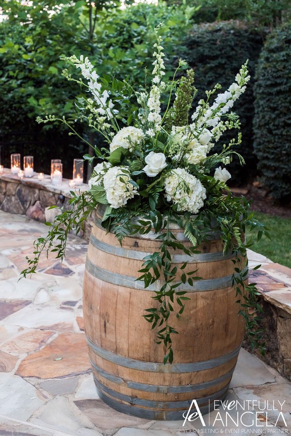 large floral arrangement on top of a wine barrel