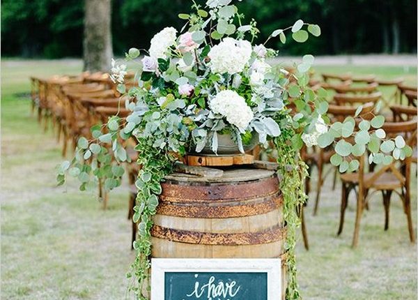 rustic wine barrel wedding decor with greenery arrangements