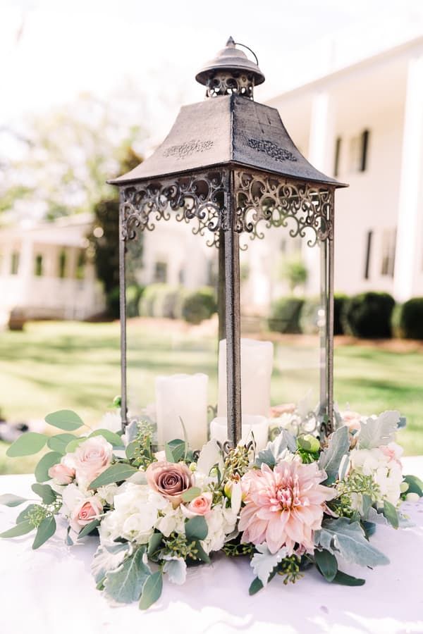 Ornate lantern center piece with pink and white flowers around base