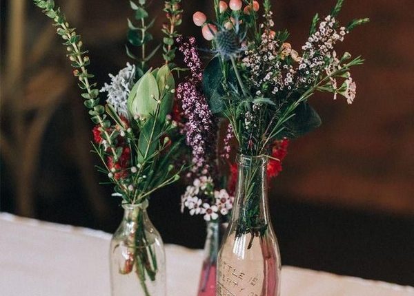 Rustic wildflower wedding centrepiece in mixed vintage bottles