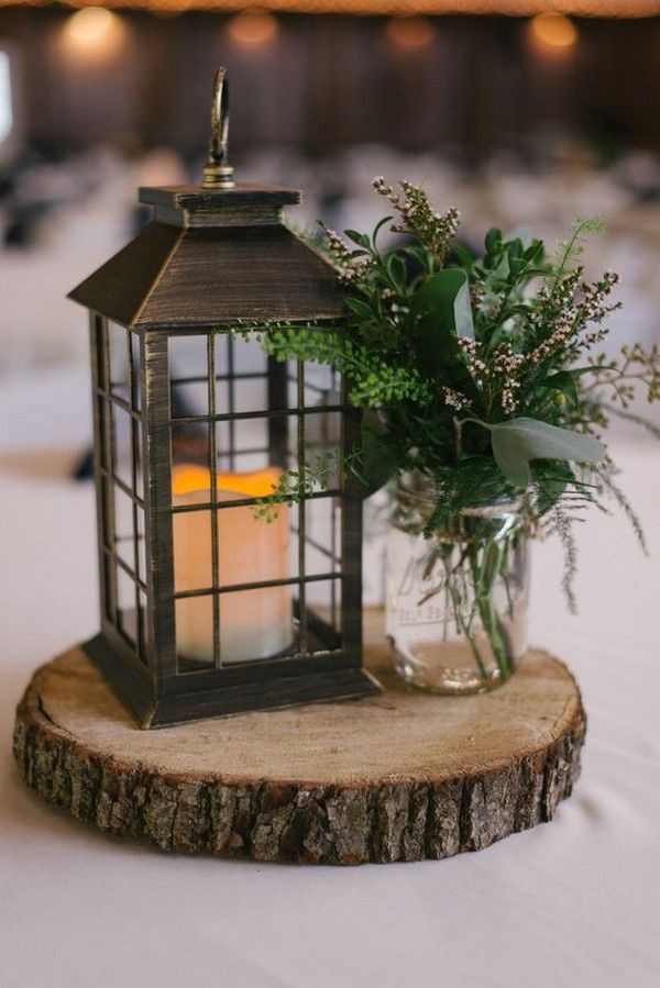black lantern, greenery and tree stump wedding centerpiece