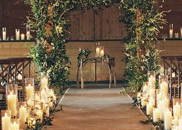 rustic indoor wedding ceremony with greenery wedding arch and candles