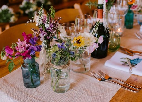 rustic tipi mixed bottles and wildflowers wedding centerpiece