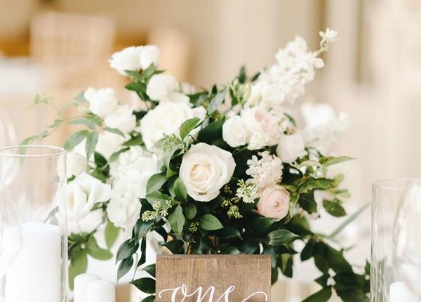 simple white and green wedding centerpiece with wood table number