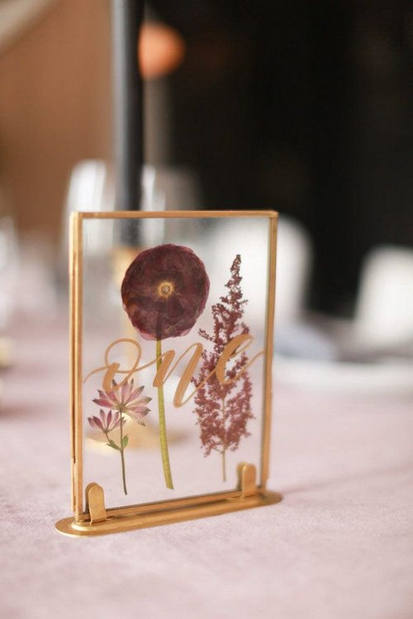 table numbers make of pressed flowers in a frame reading “one” in gold calligraphy