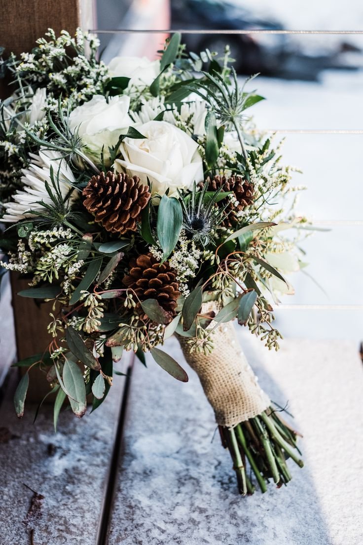 rustic winter wedding bouquet with white roses eucalyptus and pine cones