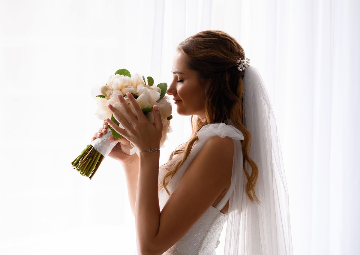 bride inwedding dress holding sniffing wedding bouquet